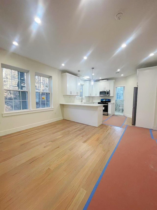 kitchen featuring appliances with stainless steel finishes, a peninsula, light wood-type flooring, white cabinetry, and recessed lighting