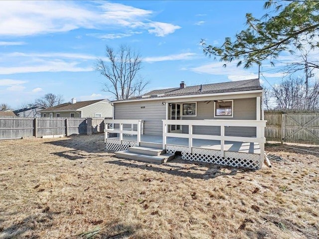 back of property with a fenced backyard, a chimney, and a wooden deck