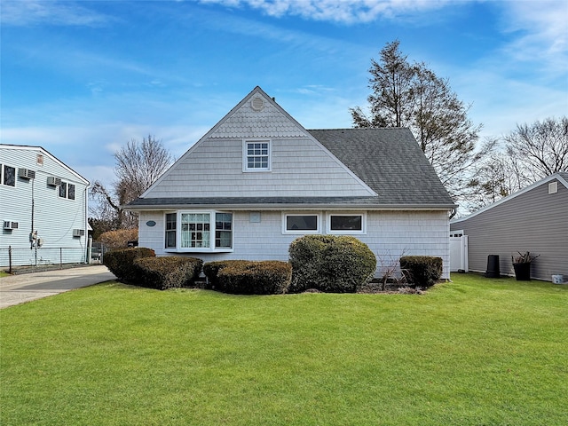 exterior space with a shingled roof and a front lawn