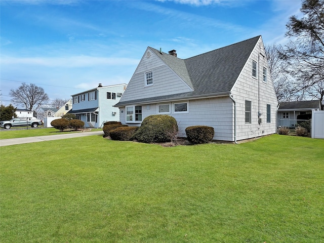 view of front facade featuring a front yard, roof with shingles, fence, and a chimney