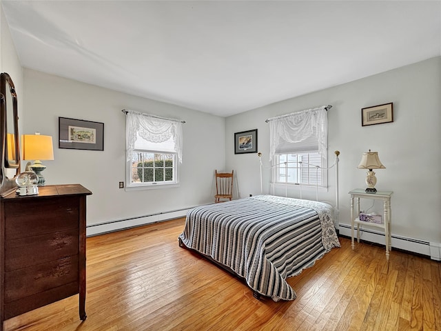 bedroom with a baseboard heating unit, multiple windows, a baseboard radiator, and hardwood / wood-style flooring