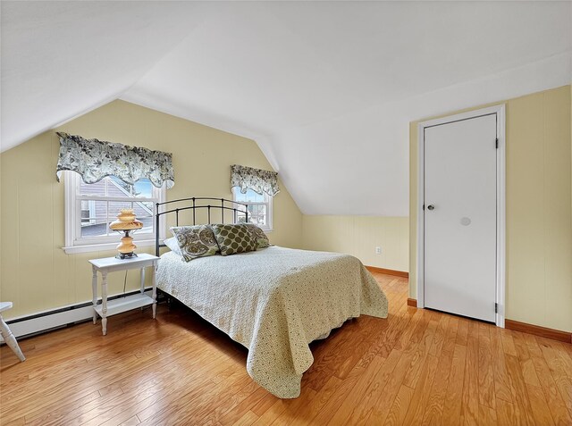 bedroom with a baseboard radiator, wood-type flooring, baseboards, and vaulted ceiling