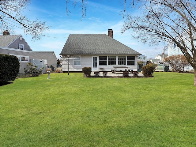 back of house with roof with shingles, a yard, a patio, a chimney, and fence