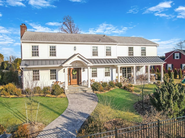 view of front of home featuring a standing seam roof, a chimney, fence, and a front yard