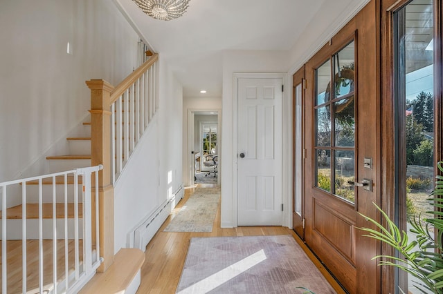 foyer entrance featuring light wood-style flooring, stairs, and baseboard heating