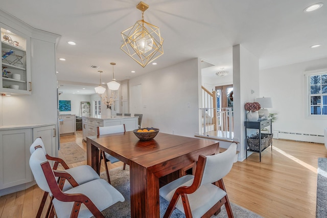 dining room featuring a chandelier, a baseboard radiator, light wood-style flooring, and stairway