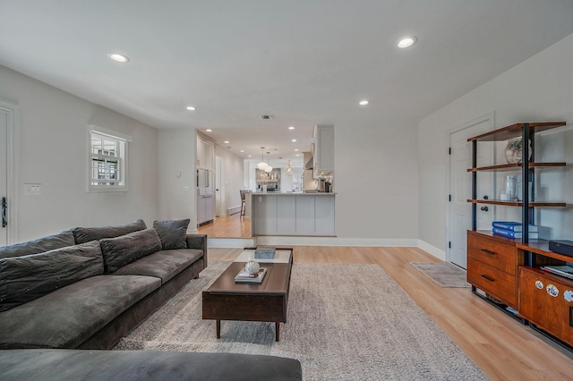 living area featuring baseboards, light wood finished floors, visible vents, and recessed lighting