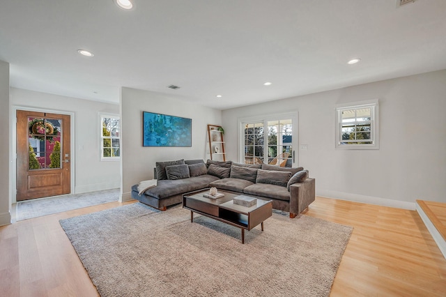 living room featuring a healthy amount of sunlight, light wood finished floors, baseboards, and recessed lighting