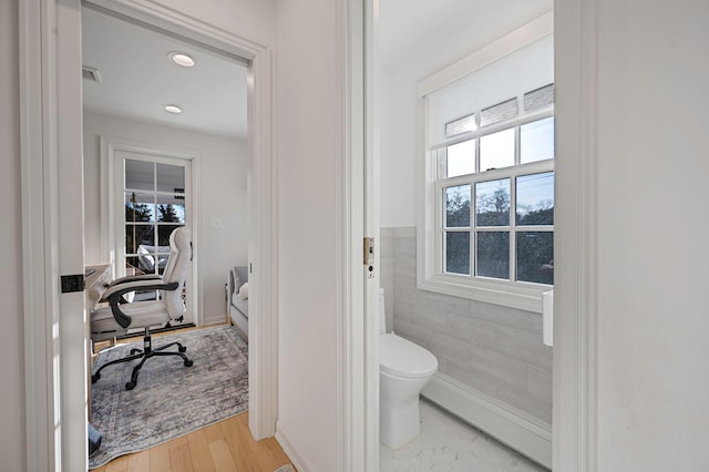 bathroom with recessed lighting, wood finished floors, toilet, and tile walls