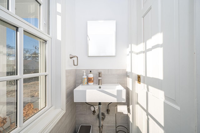 bathroom featuring a wainscoted wall, a sink, and tile walls