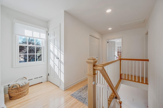 hallway featuring recessed lighting, a baseboard radiator, an upstairs landing, light wood-type flooring, and baseboards