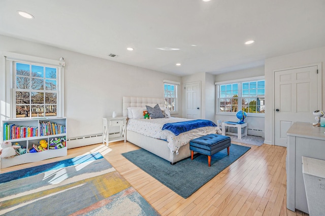 bedroom with visible vents, a baseboard heating unit, wood finished floors, and recessed lighting