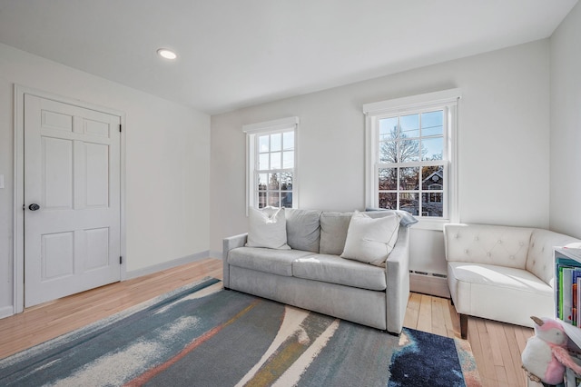 living room with a baseboard radiator, wood-type flooring, baseboards, and recessed lighting