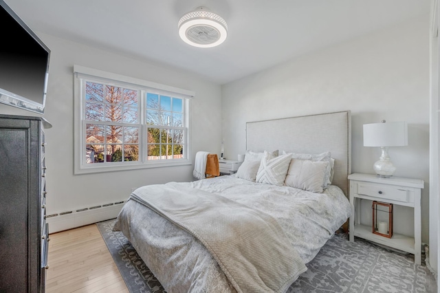 bedroom with baseboard heating and light wood-style floors