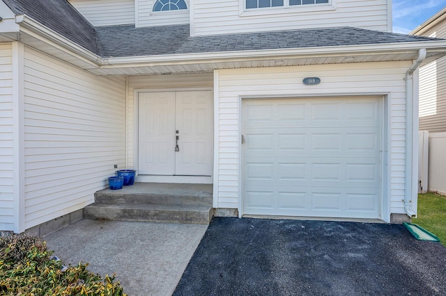 entrance to property with a shingled roof and an attached garage