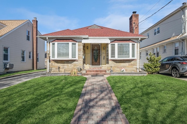 view of front of house with a chimney, stone siding, roof with shingles, and a front yard