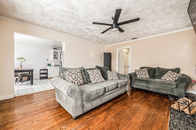 living area featuring a textured ceiling, wood finished floors, a ceiling fan, and crown molding