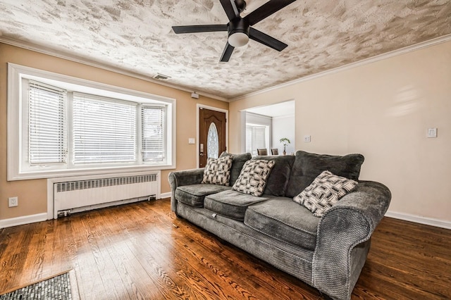 living area with visible vents, baseboards, hardwood / wood-style floors, radiator heating unit, and crown molding