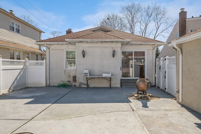 back of property with a patio area, a shingled roof, fence, and stucco siding