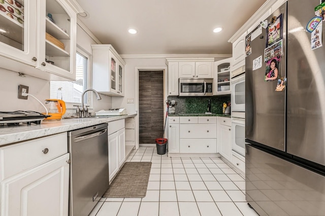 kitchen with stainless steel appliances, light tile patterned flooring, decorative backsplash, and white cabinetry