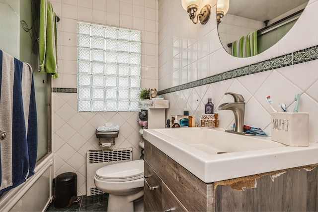 bathroom with radiator heating unit, vanity, toilet, and tile walls