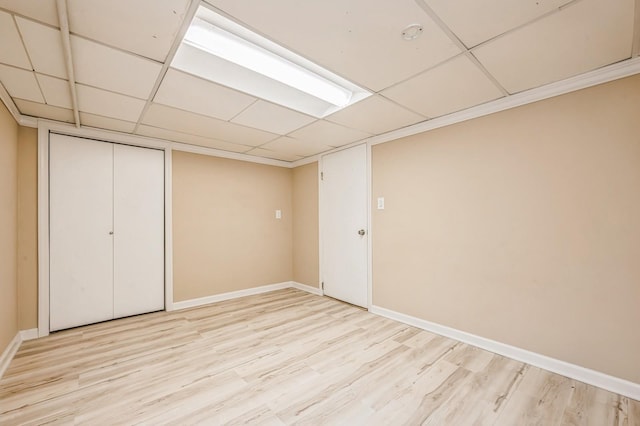 unfurnished bedroom featuring a paneled ceiling, a closet, baseboards, and light wood finished floors