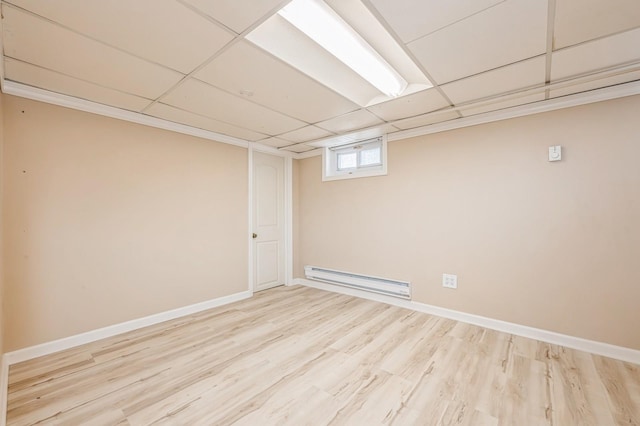 basement featuring a paneled ceiling, baseboards, baseboard heating, and wood finished floors