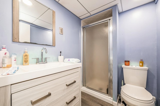 full bath featuring toilet, a shower stall, a paneled ceiling, and vanity