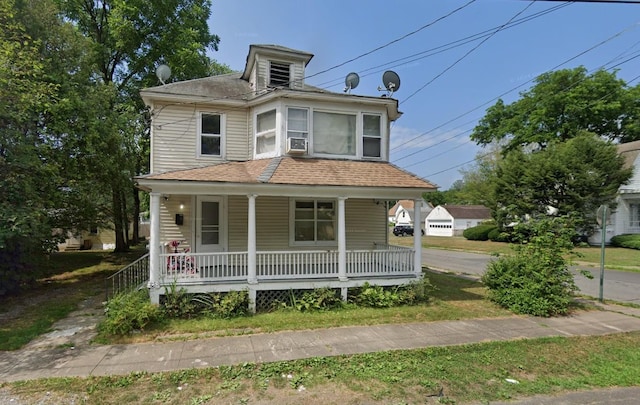 traditional style home featuring covered porch and roof with shingles