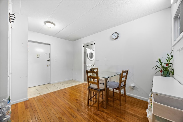 dining room with stacked washer and clothes dryer, wood-type flooring, and baseboards