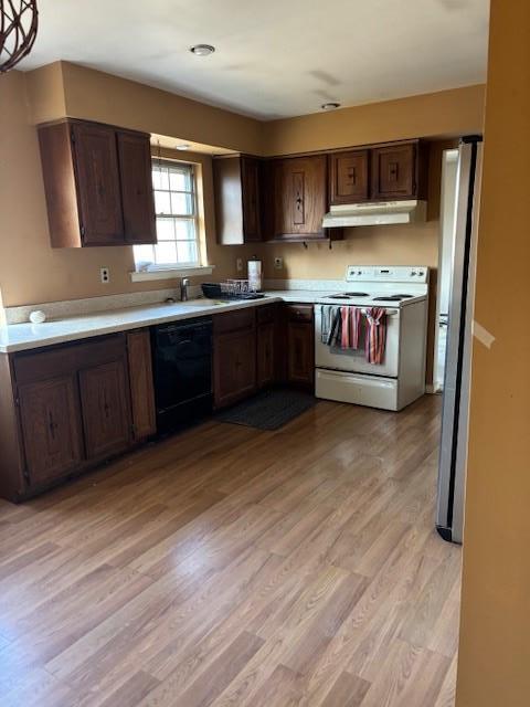 kitchen featuring white range with electric stovetop, dishwasher, freestanding refrigerator, light countertops, and under cabinet range hood