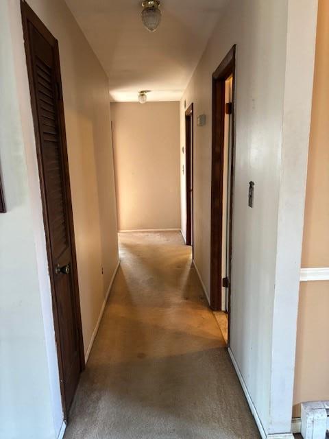 hall featuring light carpet and baseboards