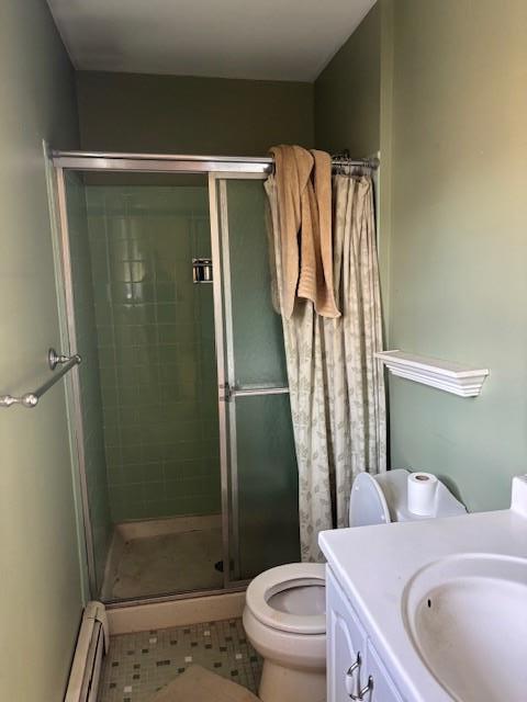 full bath with a stall shower, toilet, tile patterned flooring, baseboard heating, and vanity