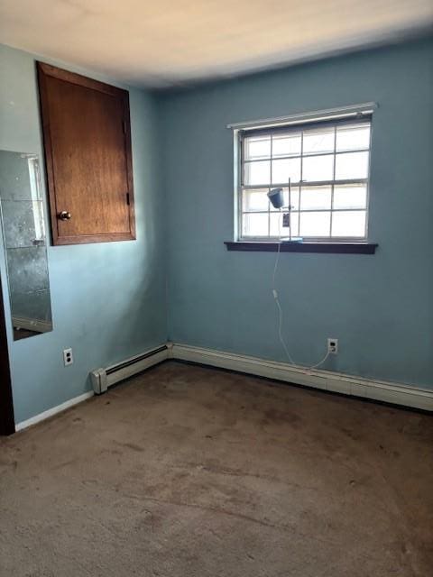 empty room featuring baseboard heating, carpet flooring, and baseboards