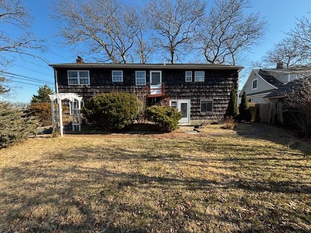 rear view of house featuring a chimney and a yard