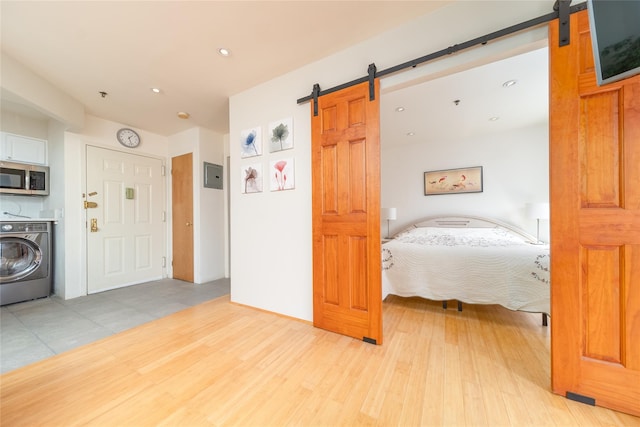 bedroom featuring light wood finished floors, a barn door, and washer / clothes dryer