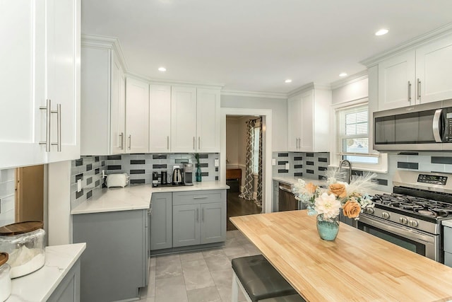 kitchen with backsplash, gray cabinetry, stainless steel appliances, and crown molding