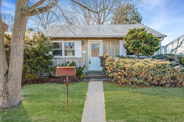 view of front of home with a shingled roof, a front lawn, and board and batten siding