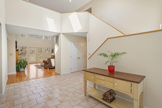 entryway featuring a towering ceiling, light tile patterned floors, and baseboards