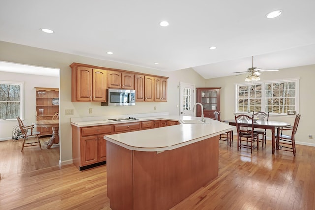 kitchen with a sink, light wood-style floors, light countertops, white electric stovetop, and stainless steel microwave