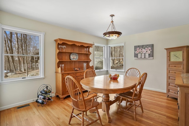 dining room featuring light wood finished floors, visible vents, and baseboards