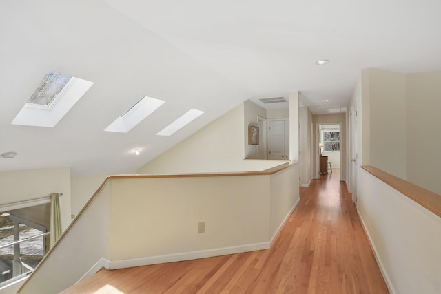 corridor with lofted ceiling, visible vents, an upstairs landing, baseboards, and light wood-type flooring