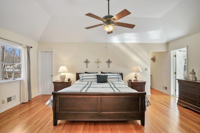 bedroom with light wood-style flooring, visible vents, vaulted ceiling, and baseboards