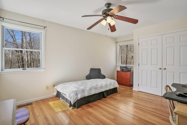 bedroom featuring light wood finished floors, a closet, visible vents, a ceiling fan, and baseboards