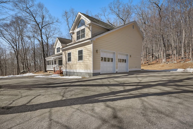 view of side of home featuring an attached garage and covered porch