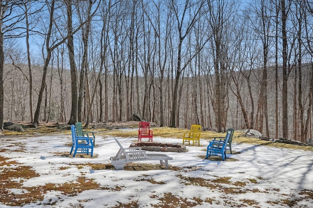 yard layered in snow featuring a wooded view