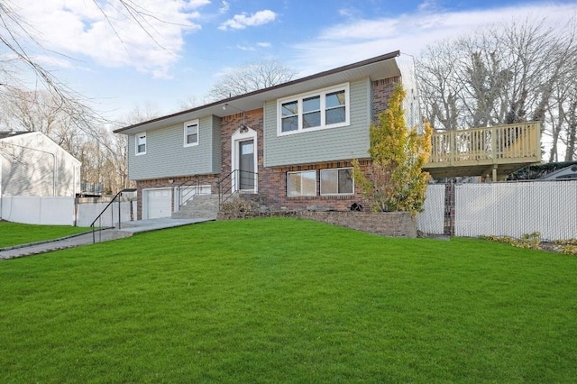 split foyer home with a front yard, brick siding, fence, and an attached garage