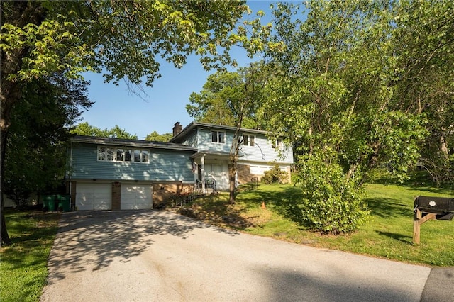 view of front facade with driveway, an attached garage, a chimney, and a front lawn