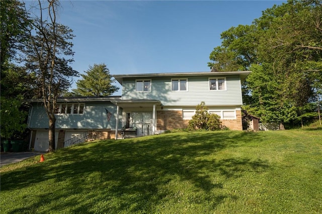 view of front facade featuring a front yard, brick siding, driveway, and an attached garage