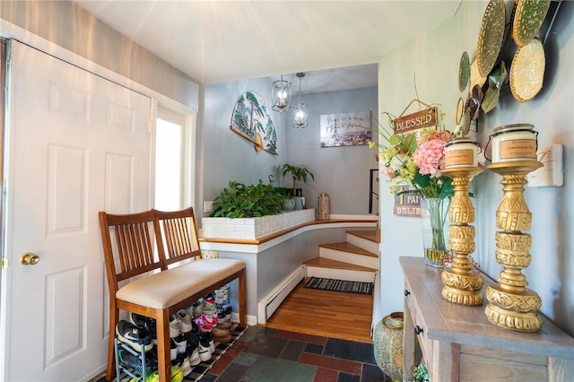 living area with a baseboard heating unit, a chandelier, and baseboards